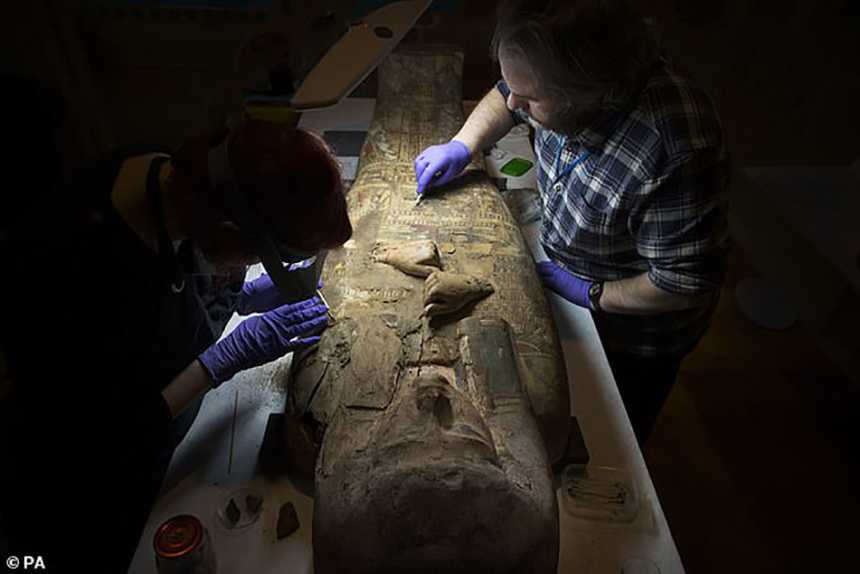 Conservators clean the front of the coffin in preparation for its presentation at the new Perth City Hall, which will open as a museum in 2022